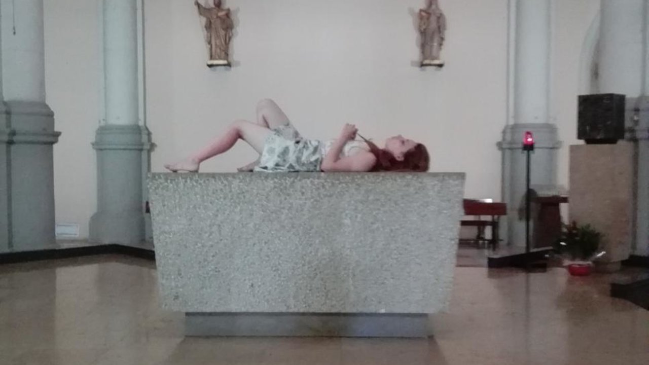 La turista tumbada en el altar de la parroquia de Sant Miquel del Port, en la Barceloneta.